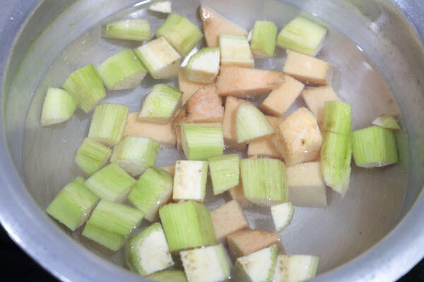 Peeled and cubed raw banana and elephant yam in water.