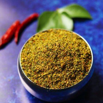 Karivepaku Podi | Andhra Curry Leaves Powder in a bowl on a blue background