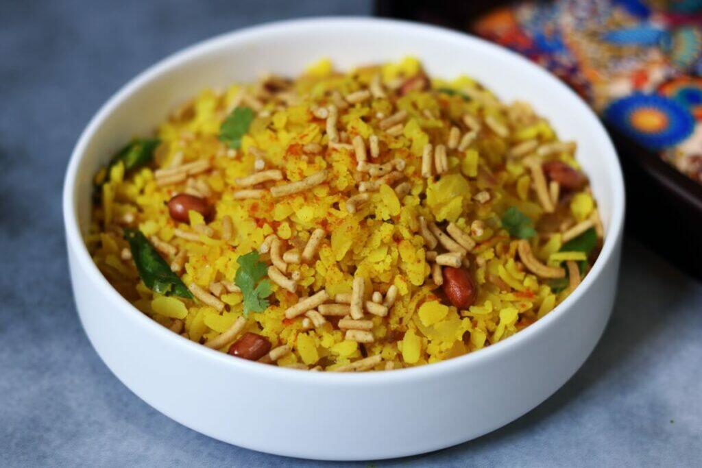 Indori Poha: Steamed poha from Indore topped with spicy sev, crunchy peanuts and tangy Jeeravan Masala