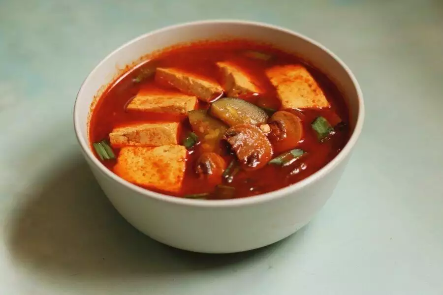 A Bowl of Vegetarian Korean Soft Tofu Stew with mushrooms and vegetables