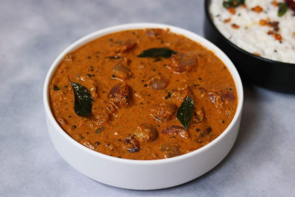 A bowl of Ulli Theeyal, the traditional Kerala dish of Shallots simmered in a roasted coconut and tamarind gravy