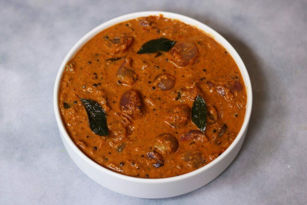 A bowl of Ulli Theeyal, the traditional Sadya dish of madras onions cooked in a coconut-tamarind gravy