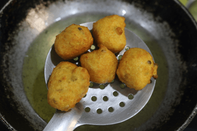 Use a slotted ladle to take the fried vadas out of the oil.
